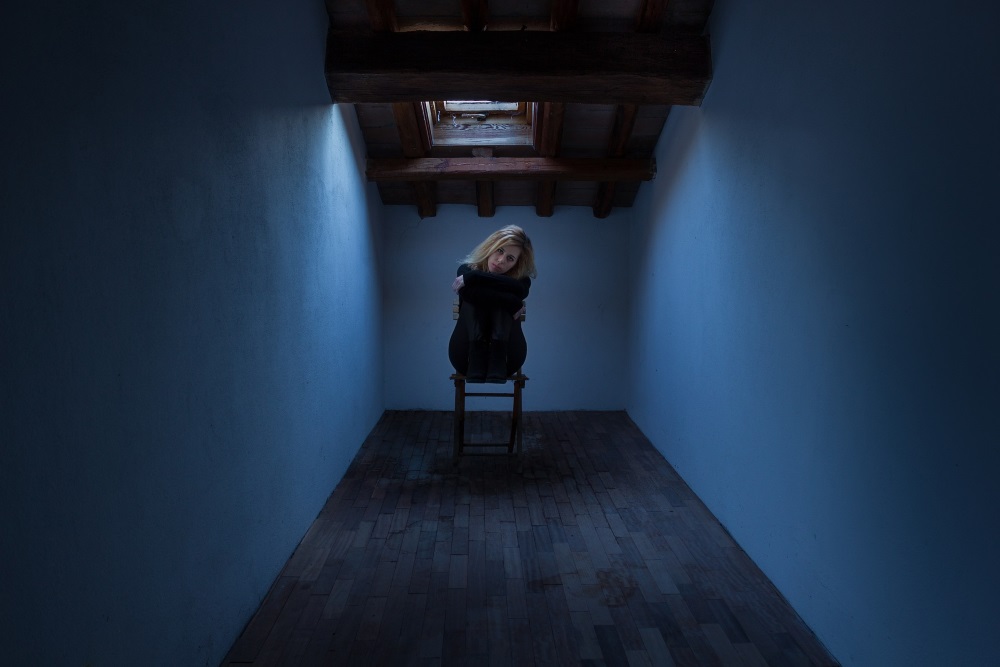 Frau sitzt auch einem Sessel in einem dunklen Raum